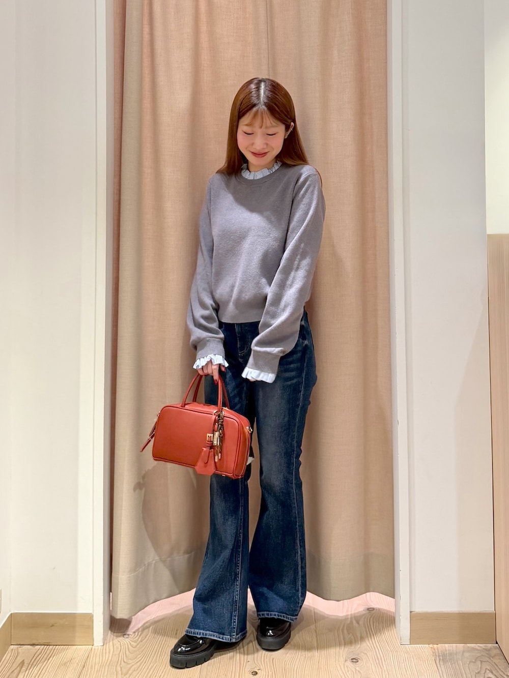 オレンジ系のボストンバッグ、ブルー系のデニムパンツ、グレー系のニット/セーターを着用したレディースの秋コーディネートの3枚目の写真