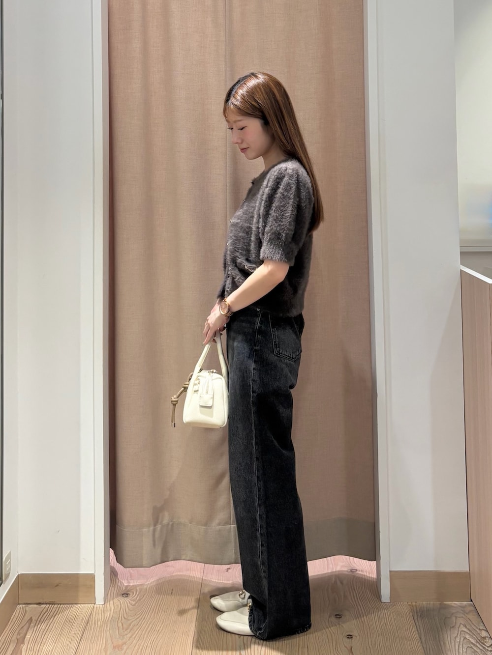 ブラック系のデニムパンツ、ホワイト系のボストンバッグ、グレー系のニット/セーターを着用したレディースの秋コーディネートの3枚目の写真