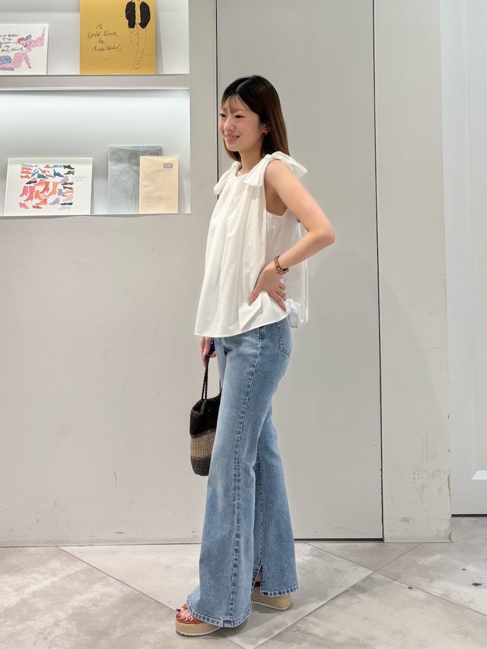 ホワイト系のシャツ/ブラウス、ゴールド系のハンドバッグ、ブルー系のデニムパンツを着用したレディースの夏コーディネートの4枚目の写真