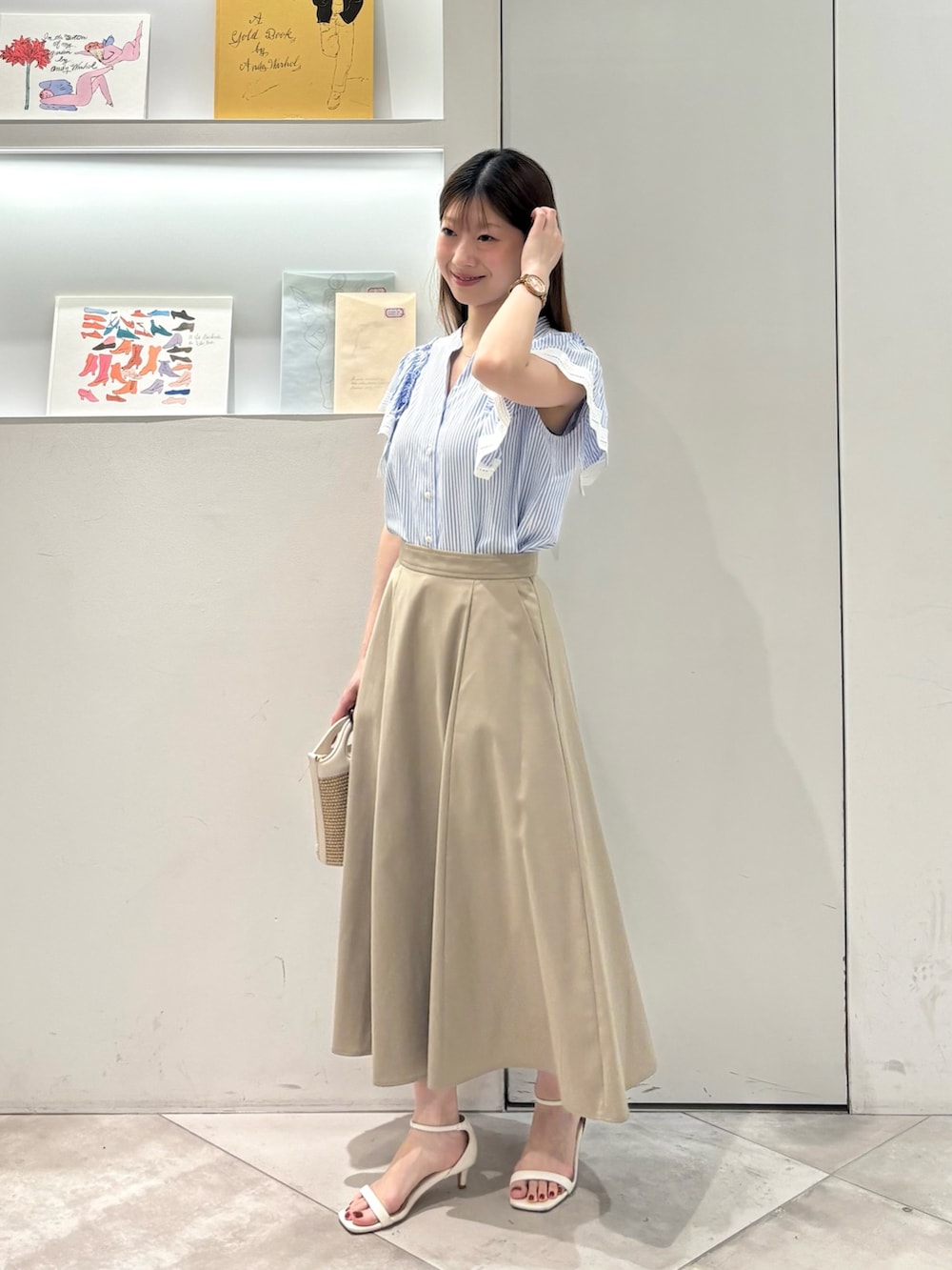 ベージュ系のスカート、ホワイト系のショルダーバッグ、ブルー系のシャツ/ブラウスを着用したレディースの夏コーディネートの3枚目の写真
