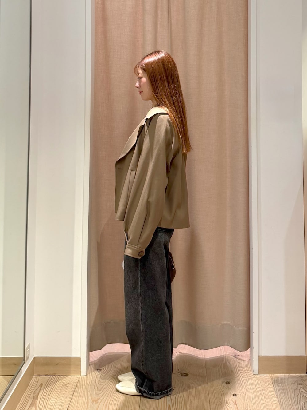 ブラック系のデニムパンツ、ブラウン系のボストンバッグ、ブラウン系のトレンチコートを着用したレディースの秋コーディネートの6枚目の写真
