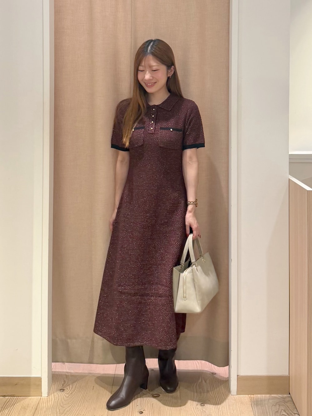 レッド系のワンピース、ベージュ系のトートバッグ、ブラウン系のブーツを着用したレディースの秋コーディネートの3枚目の写真
