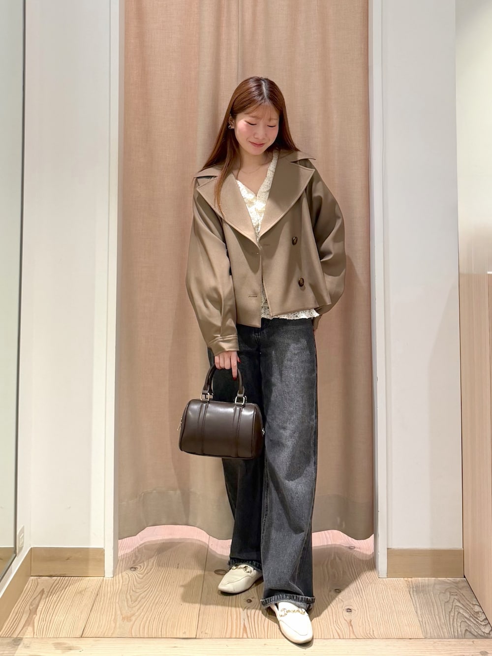ブラック系のデニムパンツ、ブラウン系のボストンバッグ、ブラウン系のトレンチコートを着用したレディースの秋コーディネートの4枚目の写真