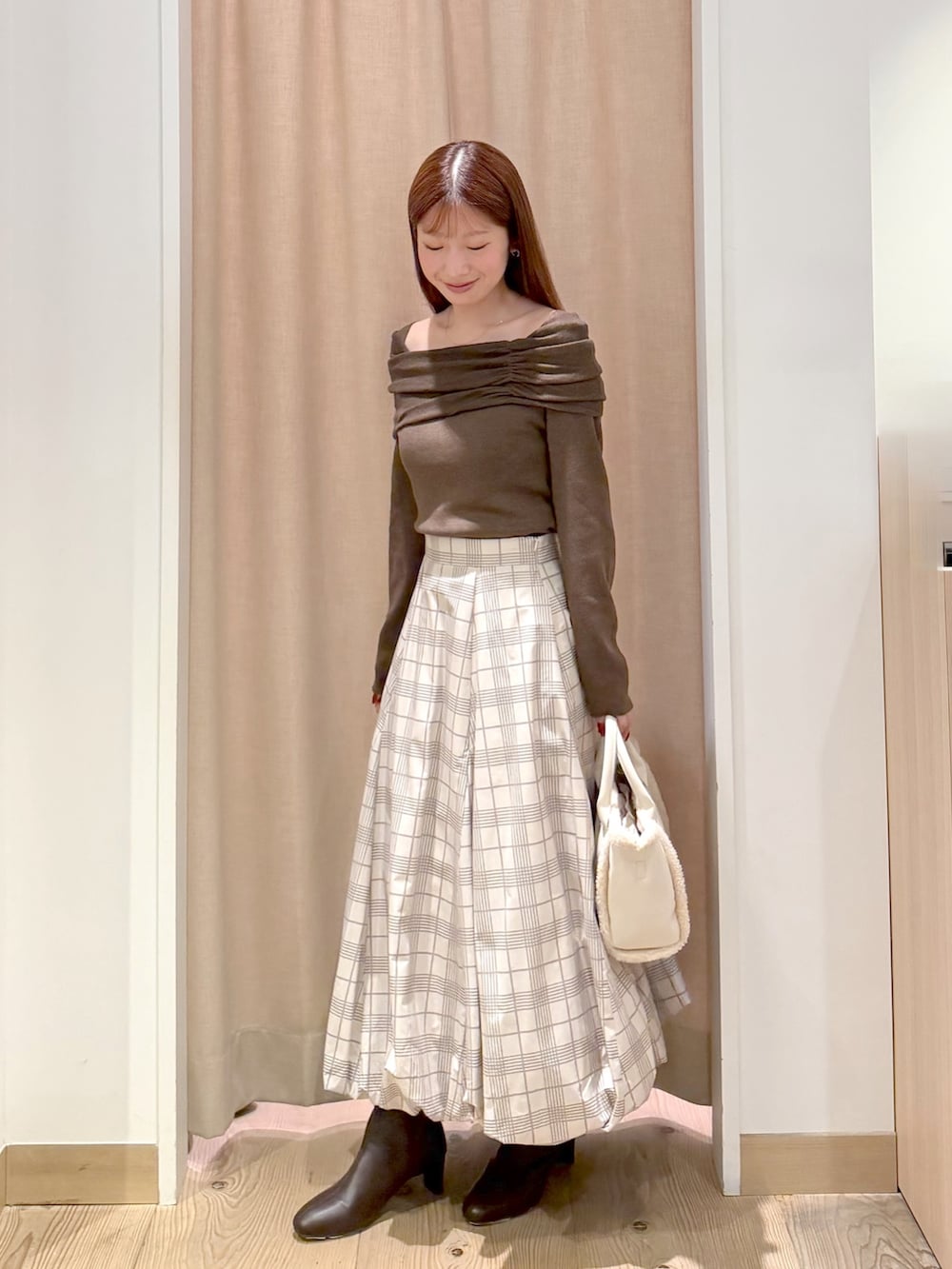 ベージュ系のスカート、ホワイト系のトートバッグ、ブラウン系のニット/セーターを着用したレディースの秋コーディネートの4枚目の写真