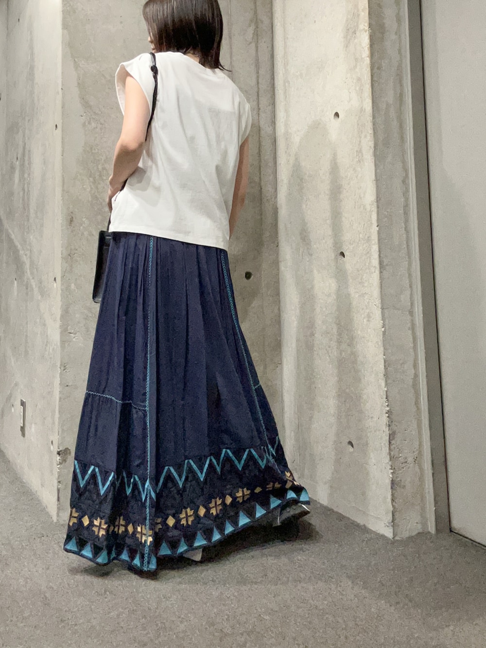 ホワイト系のTシャツ/カットソー、ブルー系のスカート、ホワイト系のスニーカーを着用したレディースの夏コーディネートの3枚目の写真