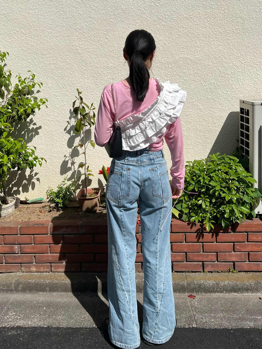 ピンク系のTシャツ/カットソー、ブルー系のデニムパンツ、ブラック系のバッグを着用したレディースの春コーディネートの3枚目の写真