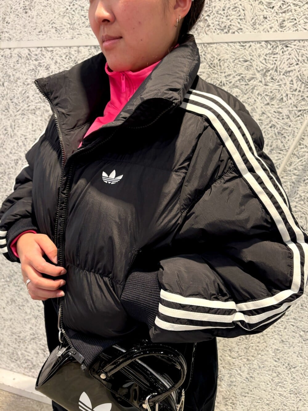 ブラック系のショルダーバッグ、ブラック系のダウンジャケット/コート、ピンク系のジャージを着用したレディースの秋コーディネートの2枚目の写真