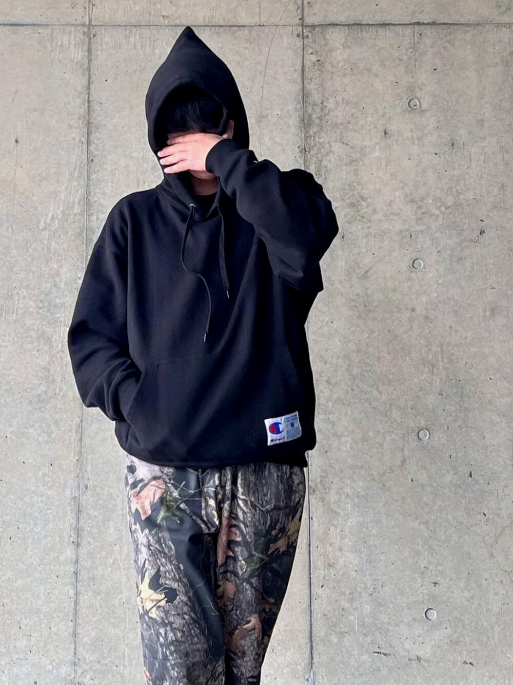 ブラウン系のスラックス、ブラック系のパーカーを着用したメンズの春コーディネートの3枚目の写真