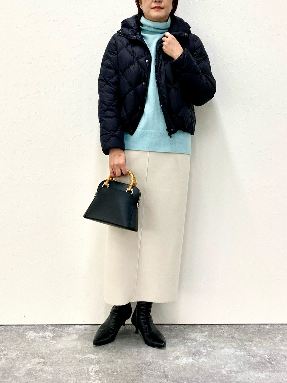 ブラック系のショルダーバッグ、ベージュ系のスカート、ブラック系のダウンジャケット/コートを着用したレディースの冬コーディネートの3枚目の写真