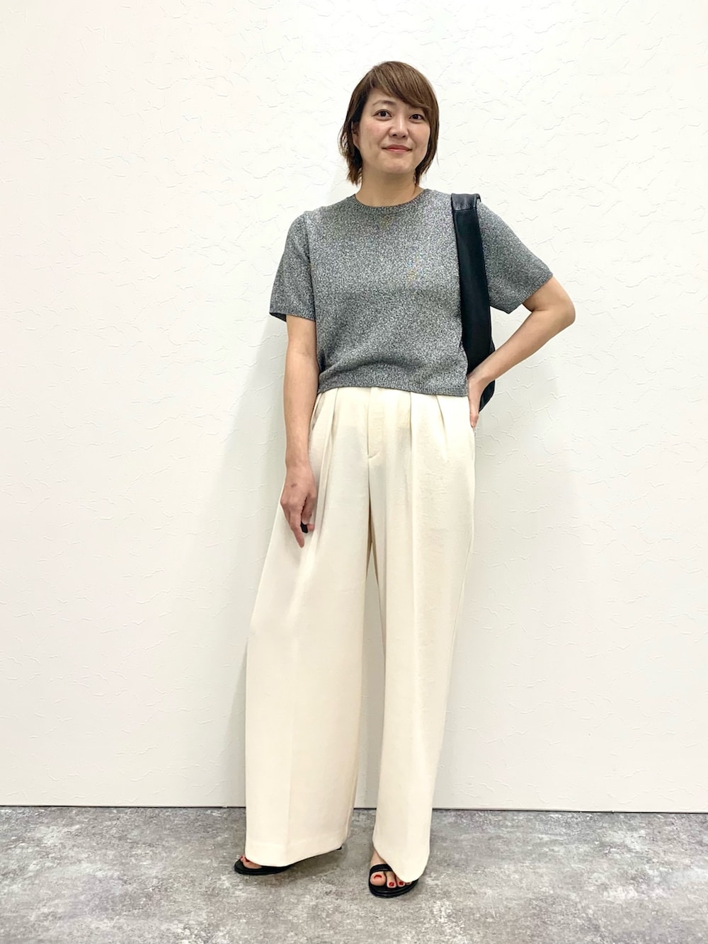 グレー系のニット/セーター、ブラック系のショルダーバッグ、ホワイト系のその他パンツを着用したレディースの春コーディネートの4枚目の写真