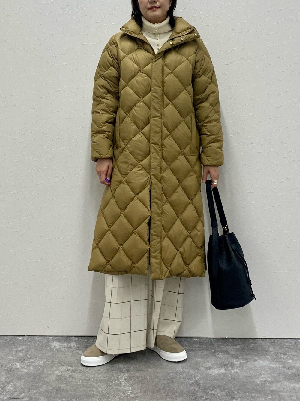 ホワイト系のニット/セーター、イエロー系のダウンジャケット/コート、ブラック系のショルダーバッグを着用したレディースの秋コーディネートの3枚目の写真