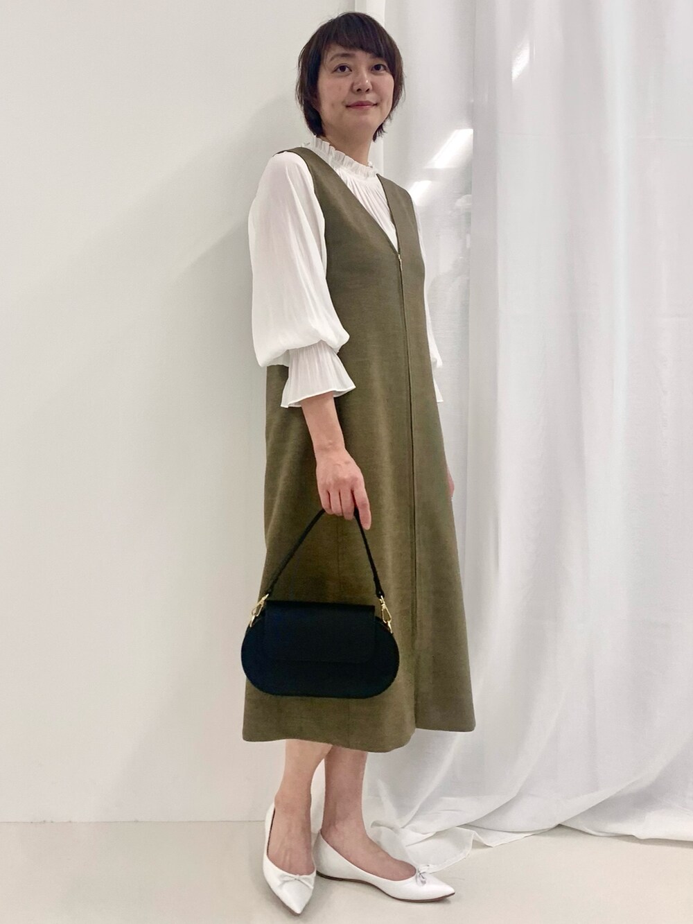 グリーン系のワンピース、ホワイト系のシャツ/ブラウス、ブラック系のショルダーバッグを着用したレディースの春コーディネートの2枚目の写真