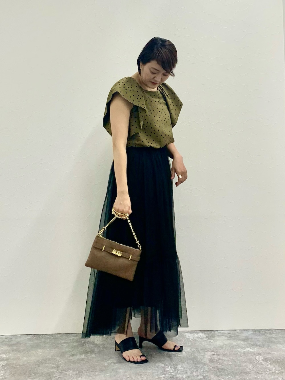 グリーン系のシャツ/ブラウス、ブラック系のスカート、ベージュ系のショルダーバッグを着用したレディースの夏コーディネートの5枚目の写真