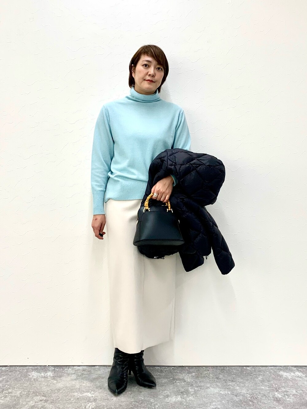 ブラック系のショルダーバッグ、ベージュ系のスカート、ブラック系のダウンジャケット/コートを着用したレディースの冬コーディネートの5枚目の写真