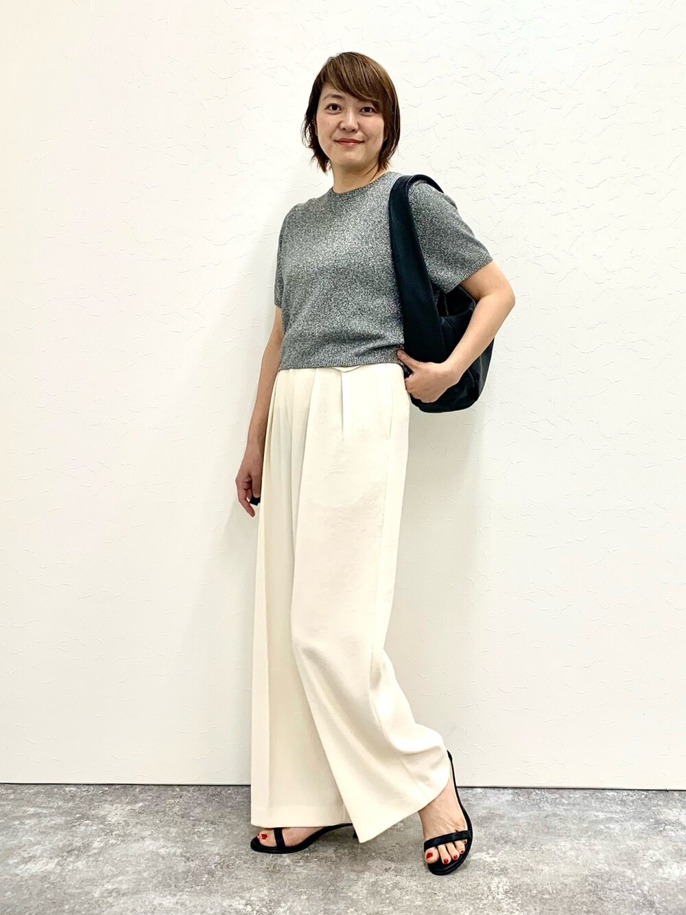 グレー系のニット/セーター、ブラック系のショルダーバッグ、ホワイト系のその他パンツを着用したレディースの春コーディネートの2枚目の写真