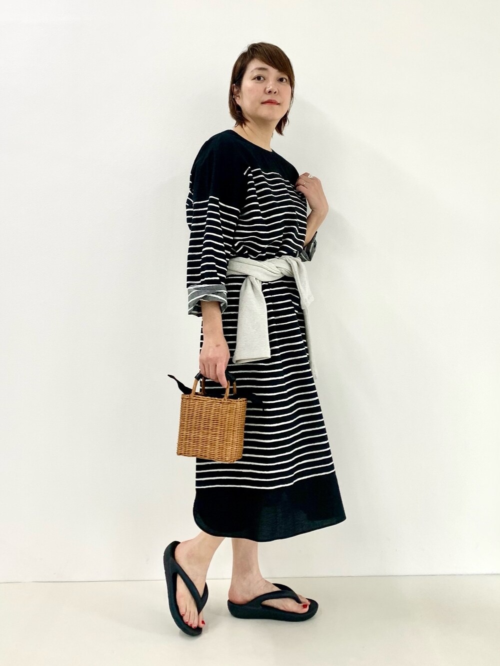 ブラック系のワンピース、グレー系のTシャツ/カットソー、ブラック系のサンダルを着用したレディースの春コーディネートの4枚目の写真