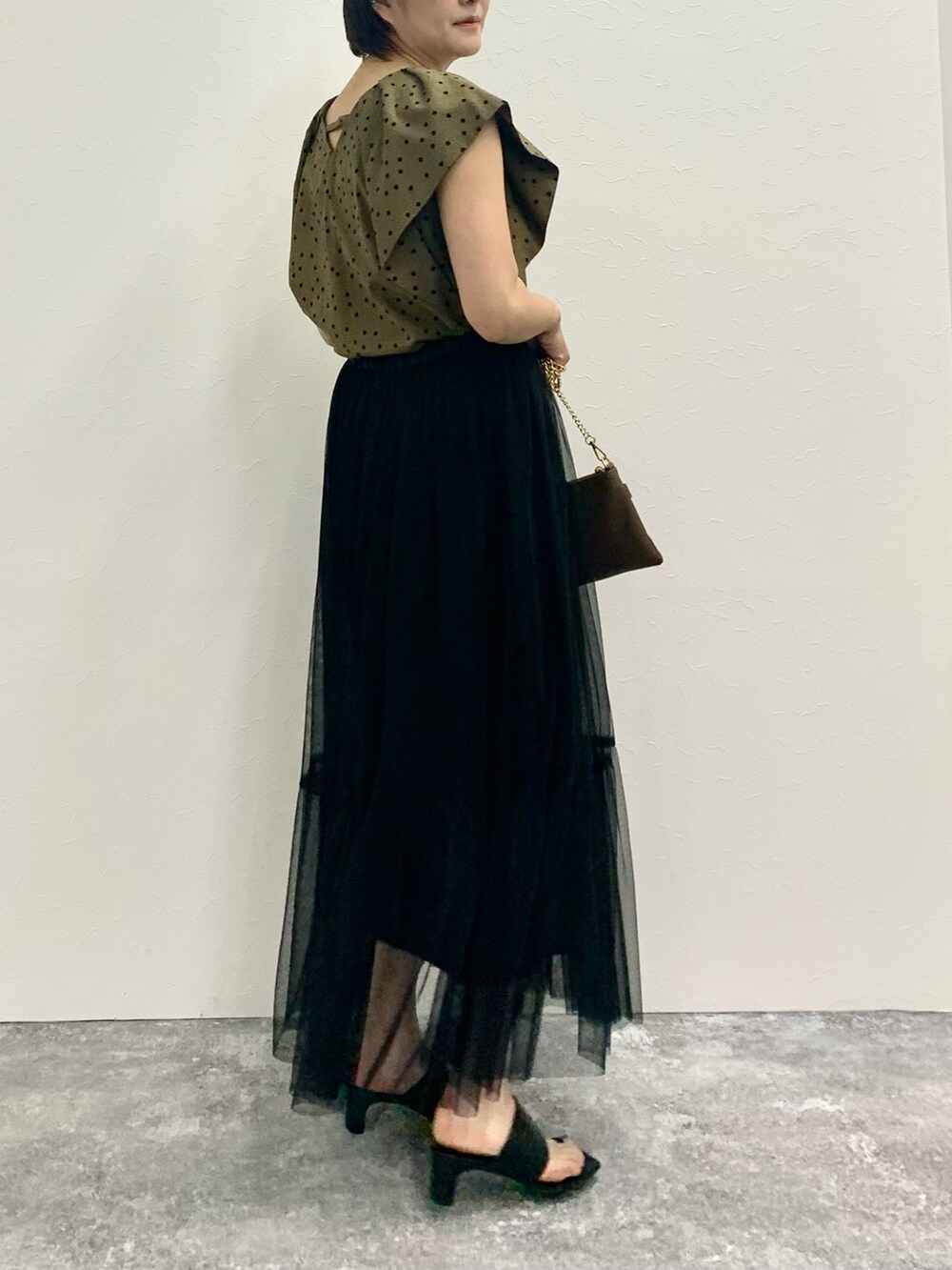 グリーン系のシャツ/ブラウス、ブラック系のスカート、ベージュ系のショルダーバッグを着用したレディースの夏コーディネートの4枚目の写真