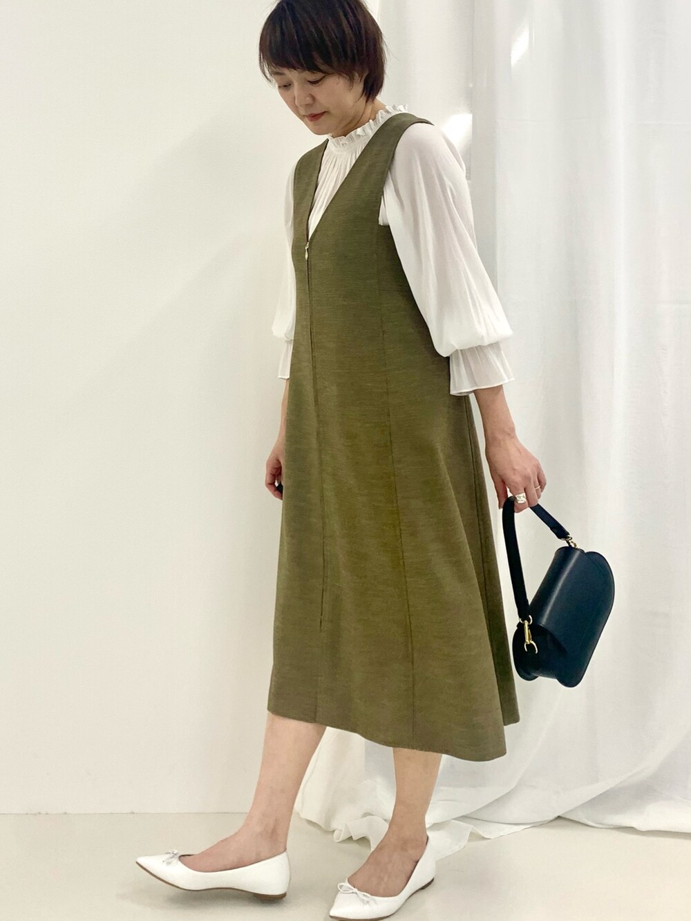 グリーン系のワンピース、ホワイト系のシャツ/ブラウス、ブラック系のショルダーバッグを着用したレディースの春コーディネートの3枚目の写真