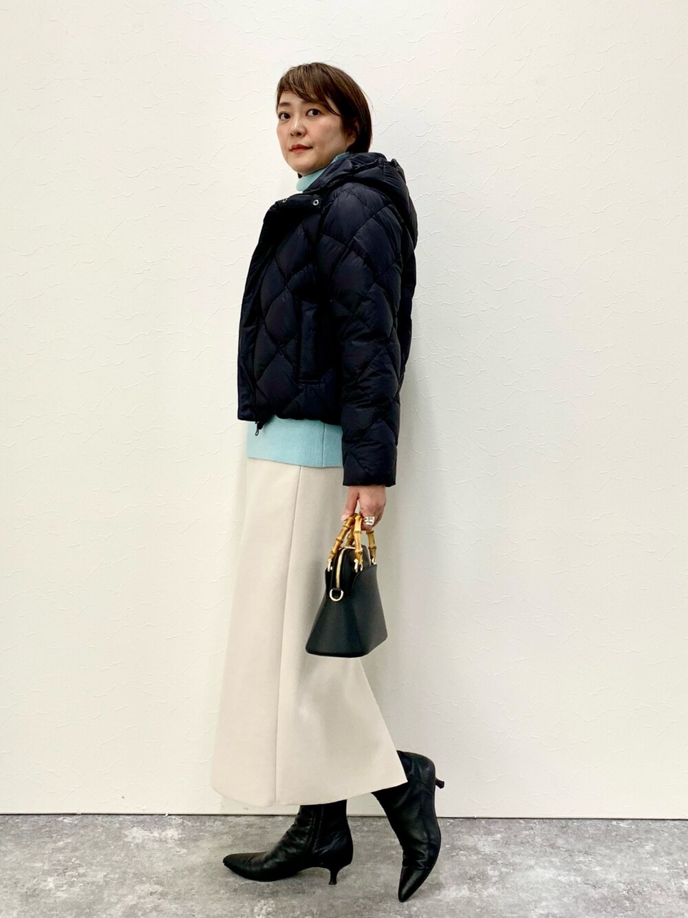 ブラック系のショルダーバッグ、ベージュ系のスカート、ブラック系のダウンジャケット/コートを着用したレディースの冬コーディネートの4枚目の写真
