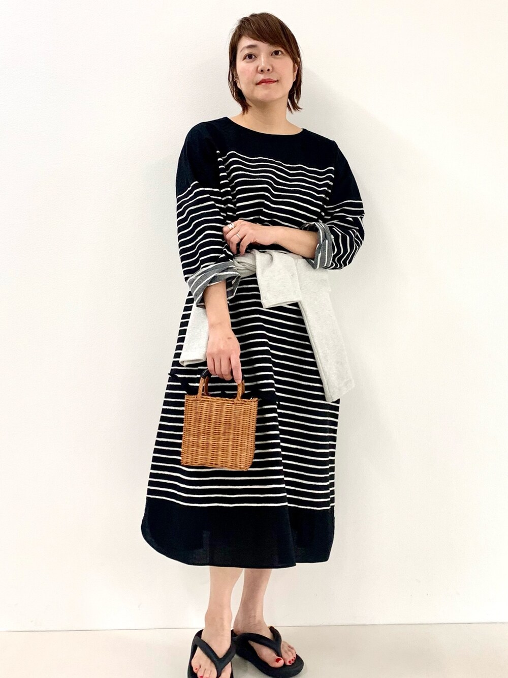 ブラック系のワンピース、グレー系のTシャツ/カットソー、ブラック系のサンダルを着用したレディースの春コーディネートの3枚目の写真