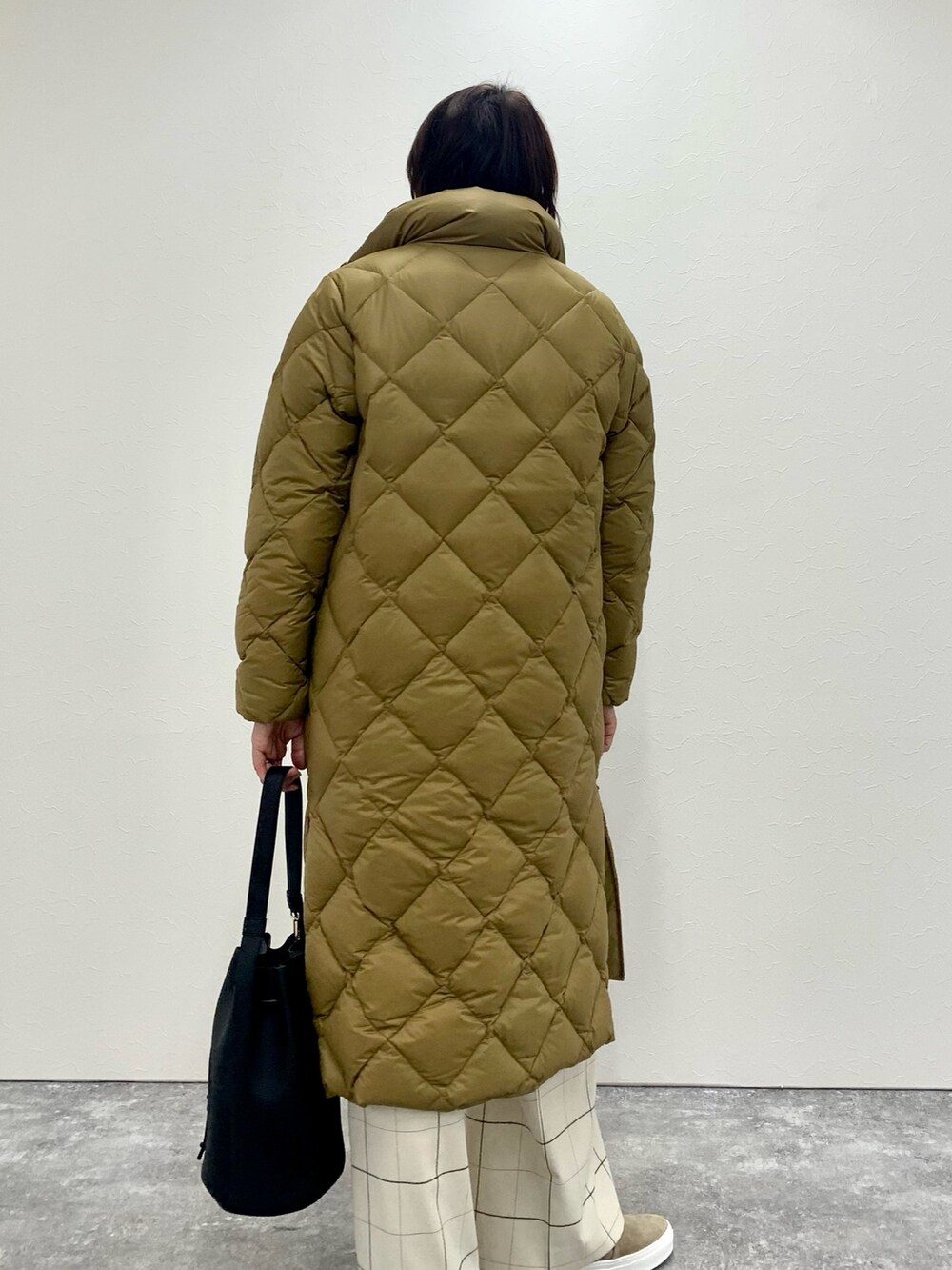 ホワイト系のニット/セーター、イエロー系のダウンジャケット/コート、ブラック系のショルダーバッグを着用したレディースの秋コーディネートの4枚目の写真