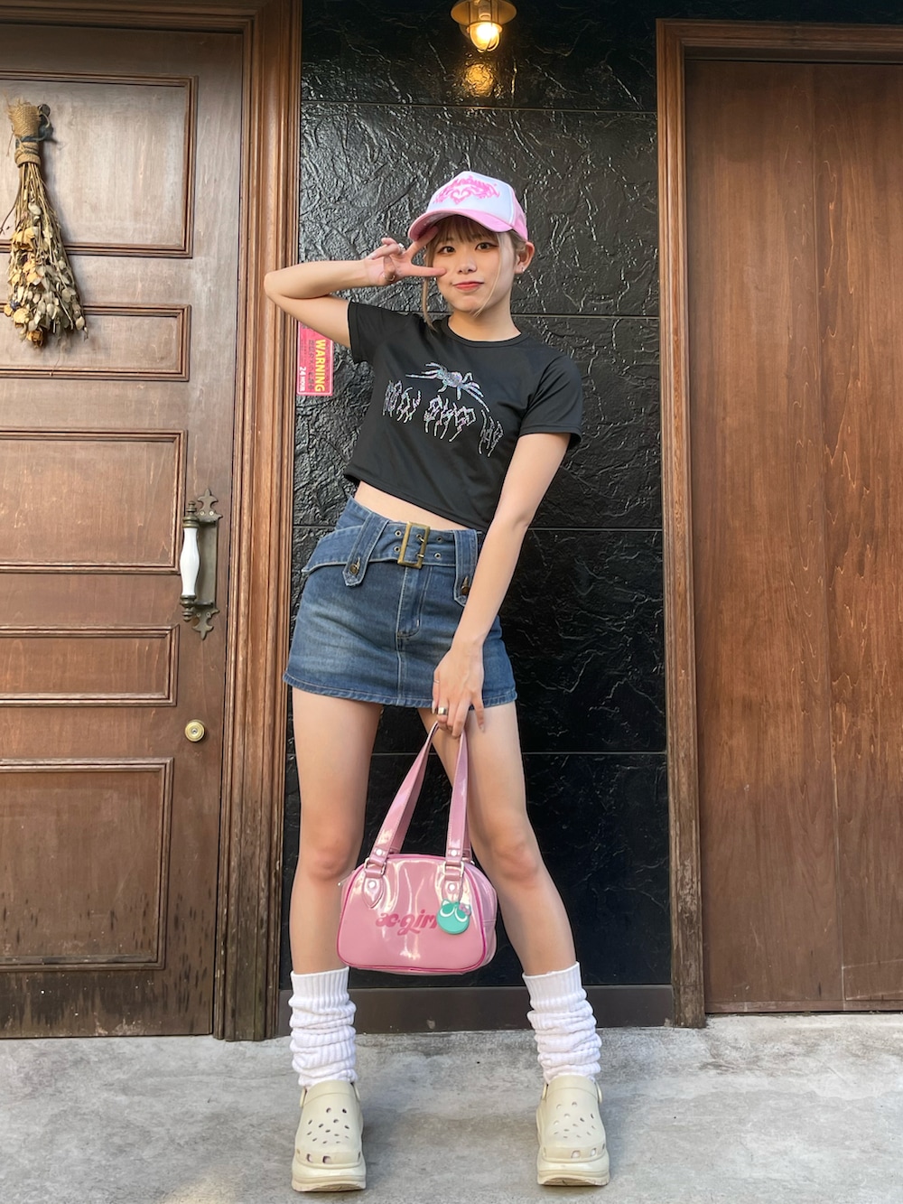 ブルー系のデニムスカート、ブラック系のTシャツ/カットソー、ベージュ系のサンダルを着用したレディースの夏コーディネートの2枚目の写真