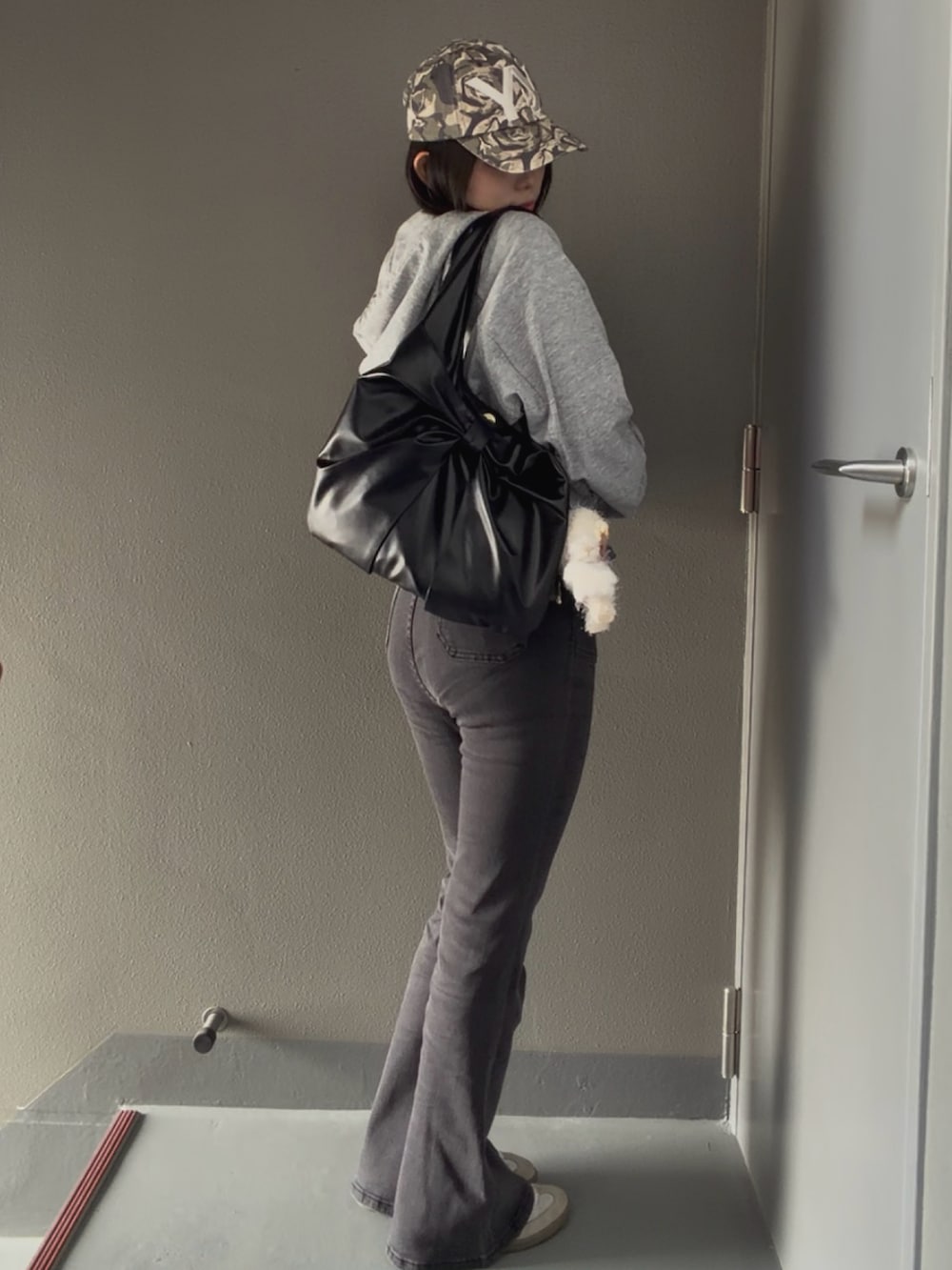 グレー系のデニムパンツ、ブラック系のトートバッグ、グレー系のパーカーを着用したレディースの春コーディネートの3枚目の写真