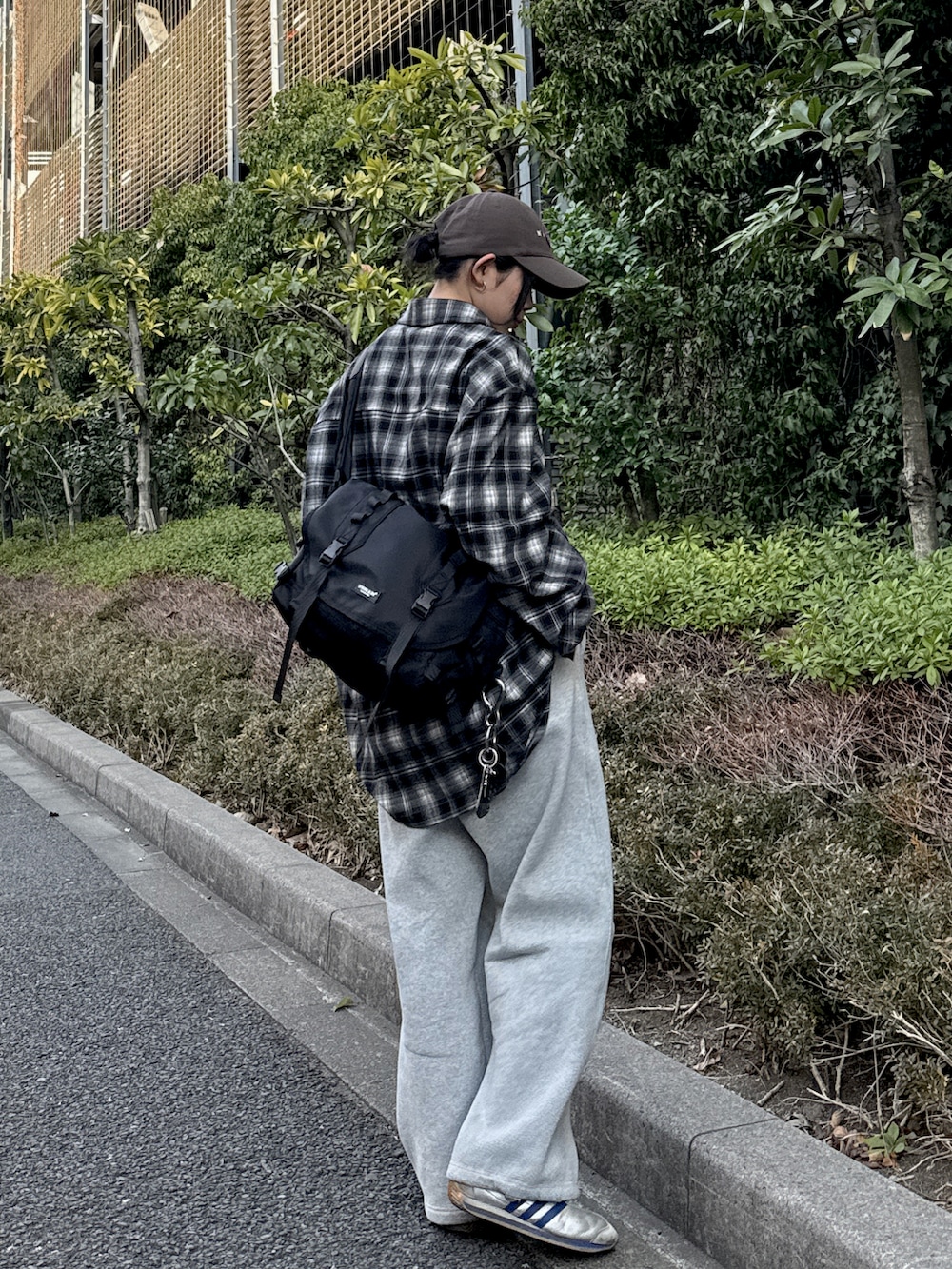 ブラック系のメッセンジャーバッグ、ブラック系のシャツ/ブラウス、グレー系のスウェットパンツを着用したレディースの春コーディネートの2枚目の写真