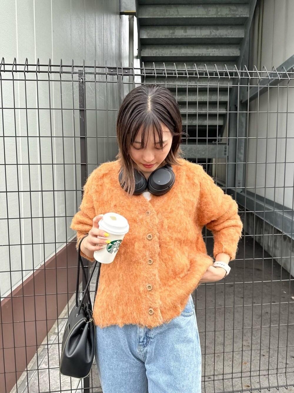 オレンジ系のカーディガン/ボレロ、ブルー系のデニムパンツを着用したレディースの秋コーディネートの2枚目の写真