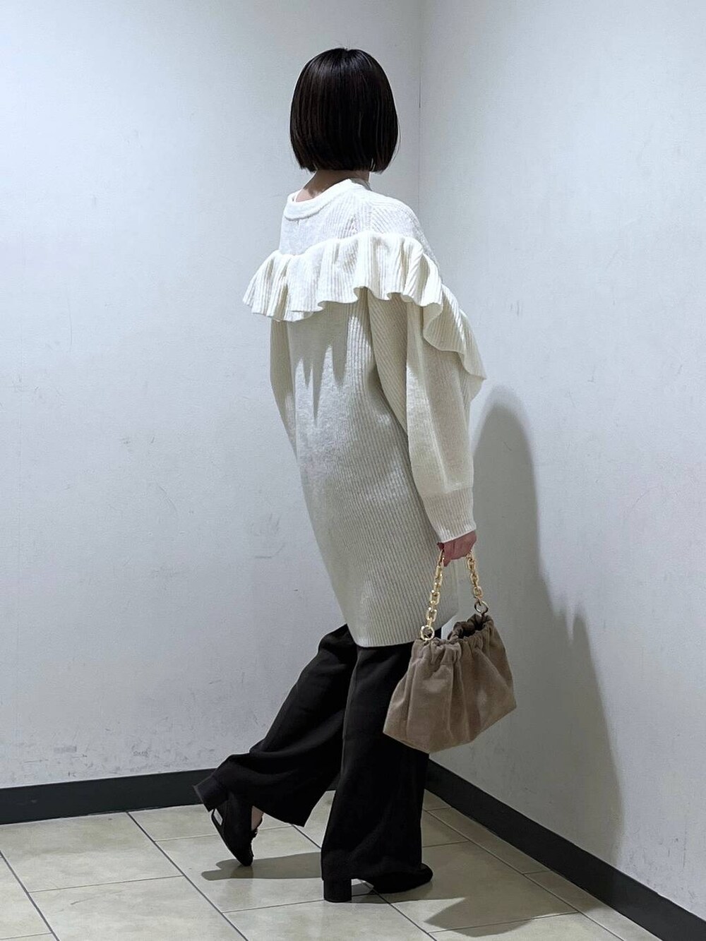 ベージュ系のショルダーバッグ、ブラウン系のスラックス、ホワイト系のワンピースを着用したレディースの冬コーディネートの3枚目の写真