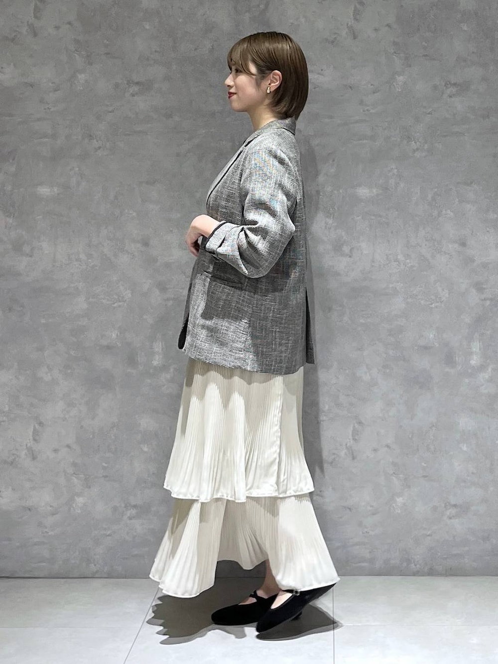 ホワイト系のスカート、ブラック系のテーラードジャケット、ブラック系のバレエシューズを着用したレディースの秋コーディネートの2枚目の写真