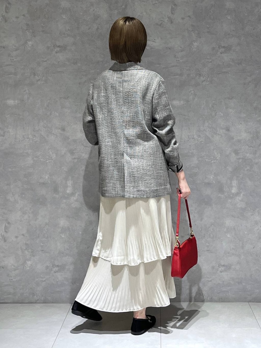 ホワイト系のスカート、ブラック系のテーラードジャケット、ブラック系のバレエシューズを着用したレディースの秋コーディネートの3枚目の写真