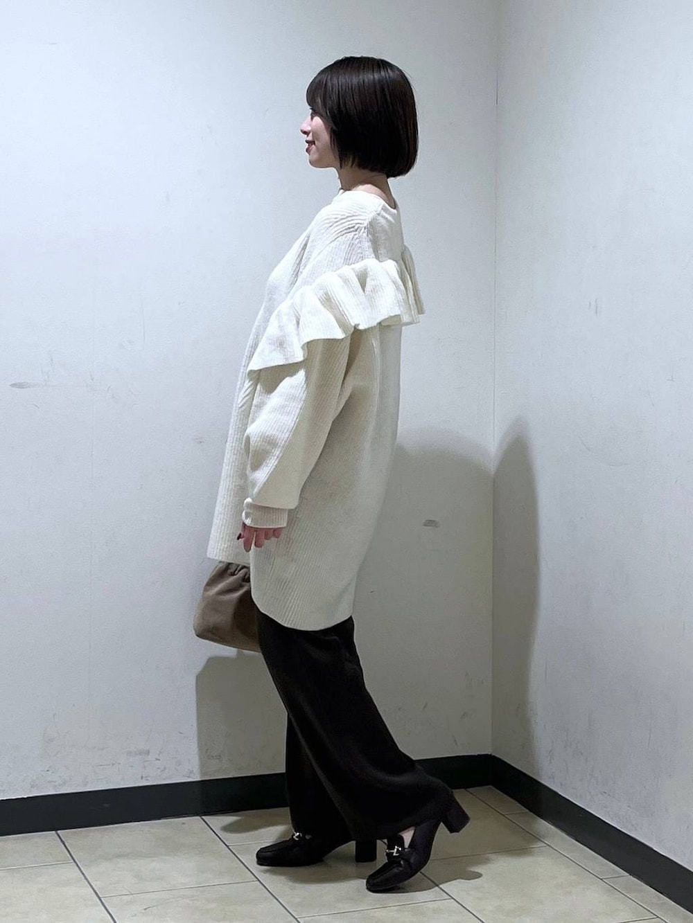 ベージュ系のショルダーバッグ、ブラウン系のスラックス、ホワイト系のワンピースを着用したレディースの冬コーディネートの2枚目の写真