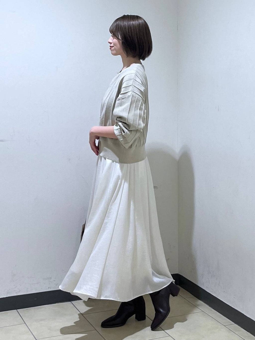 ブラウン系のブーツ、ベージュ系のカーディガン/ボレロ、ホワイト系のスカートを着用したレディースの秋コーディネートの2枚目の写真