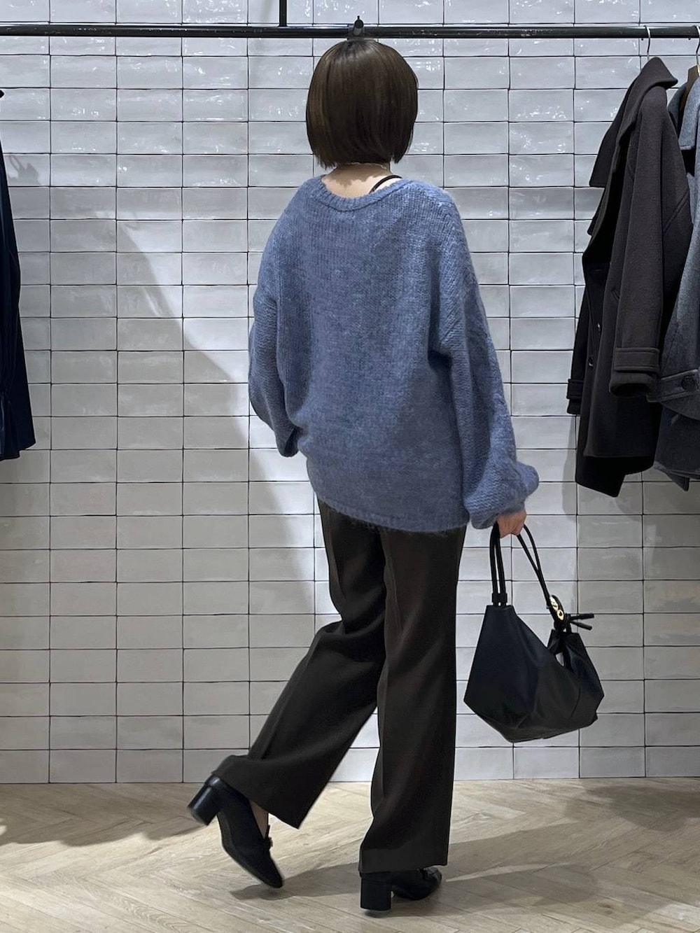 ブルー系のニット/セーター、ブラック系のショルダーバッグ、シルバー系のネックレスを着用したレディースの秋コーディネートの2枚目の写真