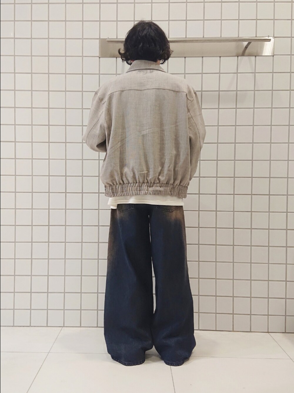 ベージュ系のブルゾン、ホワイト系のTシャツ/カットソー、ブルー系のデニムパンツを着用したメンズの秋コーディネートの2枚目の写真