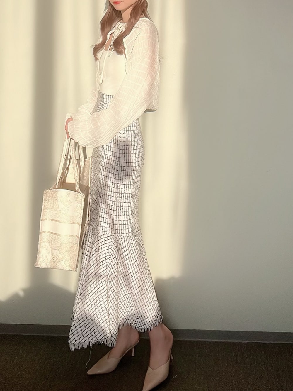 ホワイト系のスカート、ホワイト系のカーディガン/ボレロ、ホワイト系のキャミソールを着用したレディースの秋コーディネートの2枚目の写真