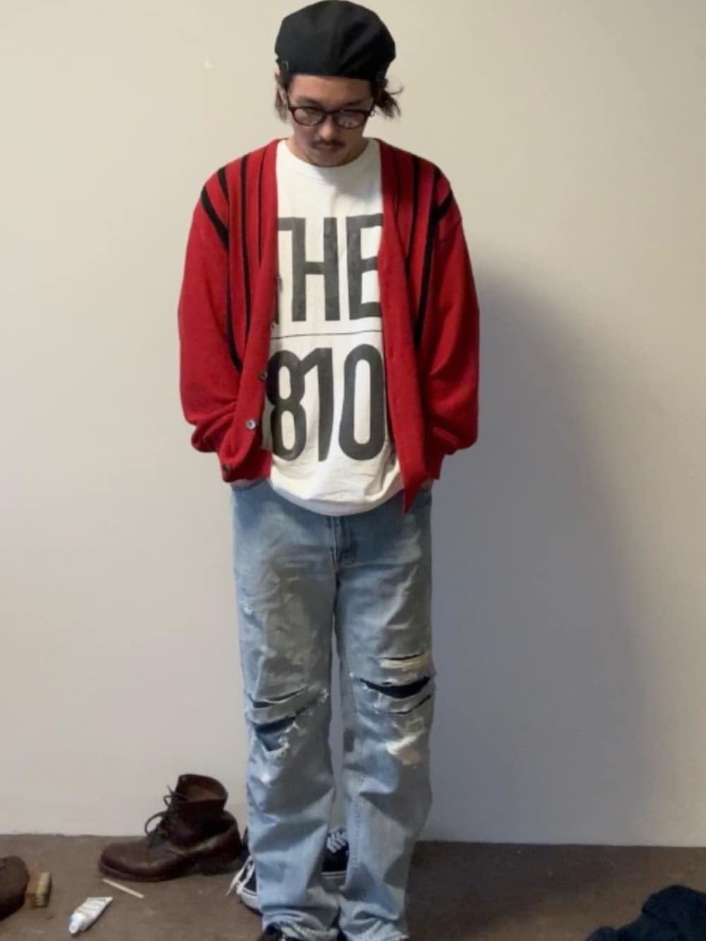 レッド系のカーディガン/ボレロ、ブルー系のデニムパンツ、ブラック系のドレスシューズを着用したメンズの秋コーディネートの2枚目の写真