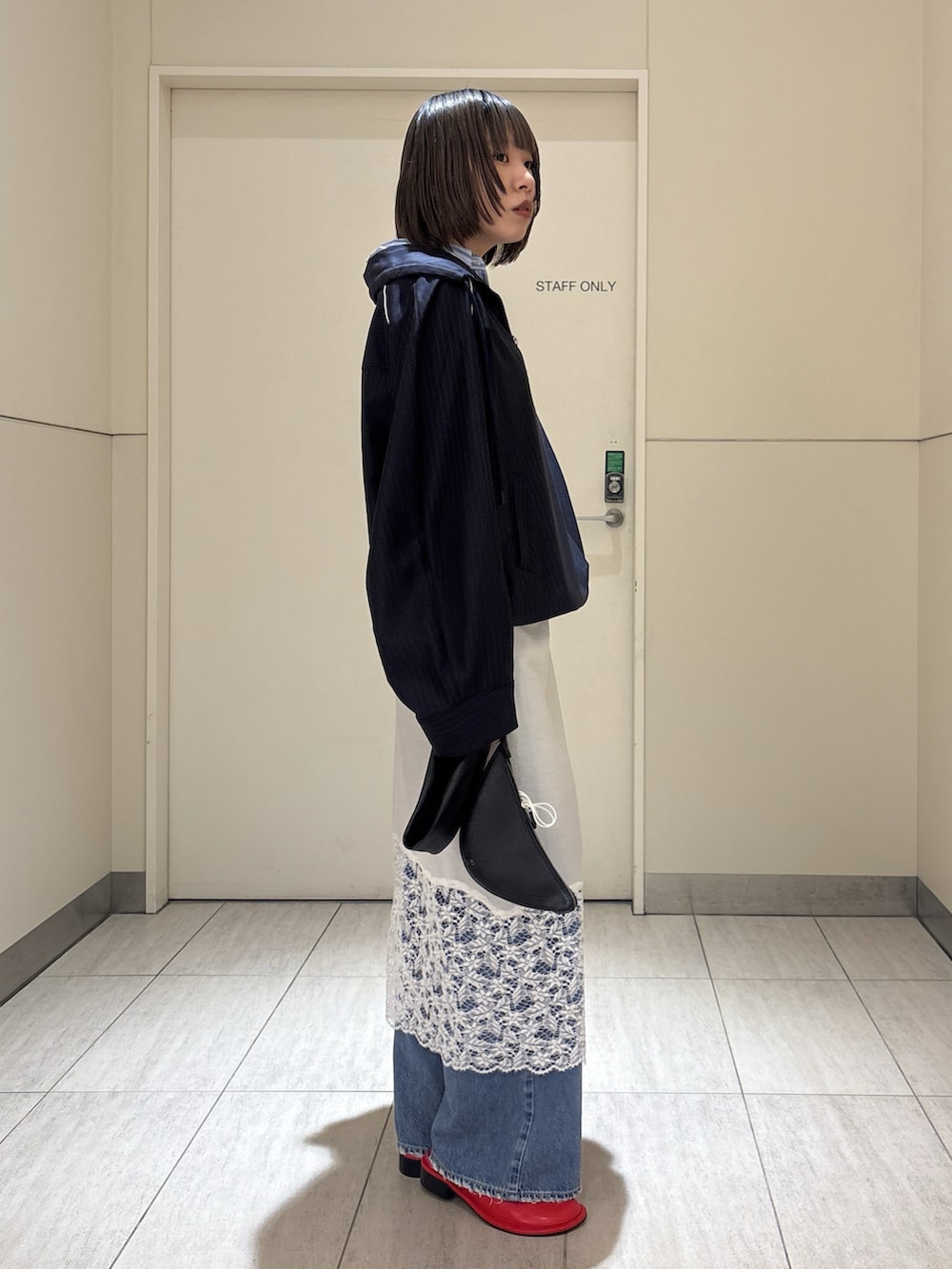 ブルー系のデニムパンツ、ホワイト系のシャツ/ブラウス、ブラック系のクラッチバッグを着用したレディースの春コーディネートの2枚目の写真