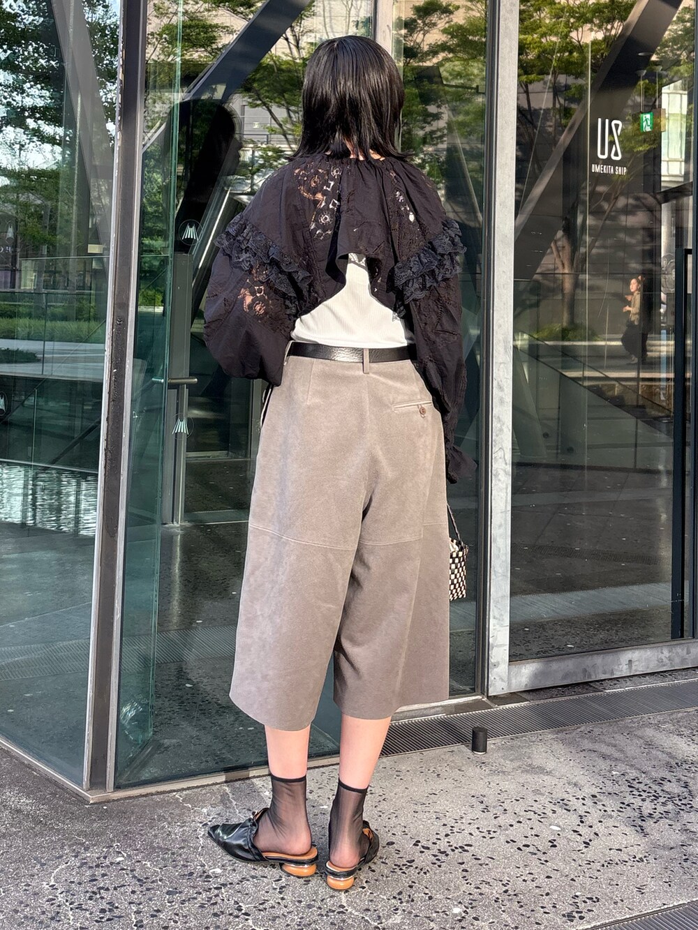 ベージュ系のその他パンツ、ブラック系のパンプス、ブラック系のかごバッグを着用したレディースの夏コーディネートの2枚目の写真