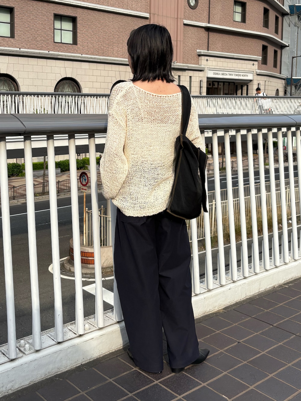 ベージュ系のニット/セーター、ブラック系のトートバッグ、ブルー系のパンツを着用したレディースの夏コーディネートの2枚目の写真