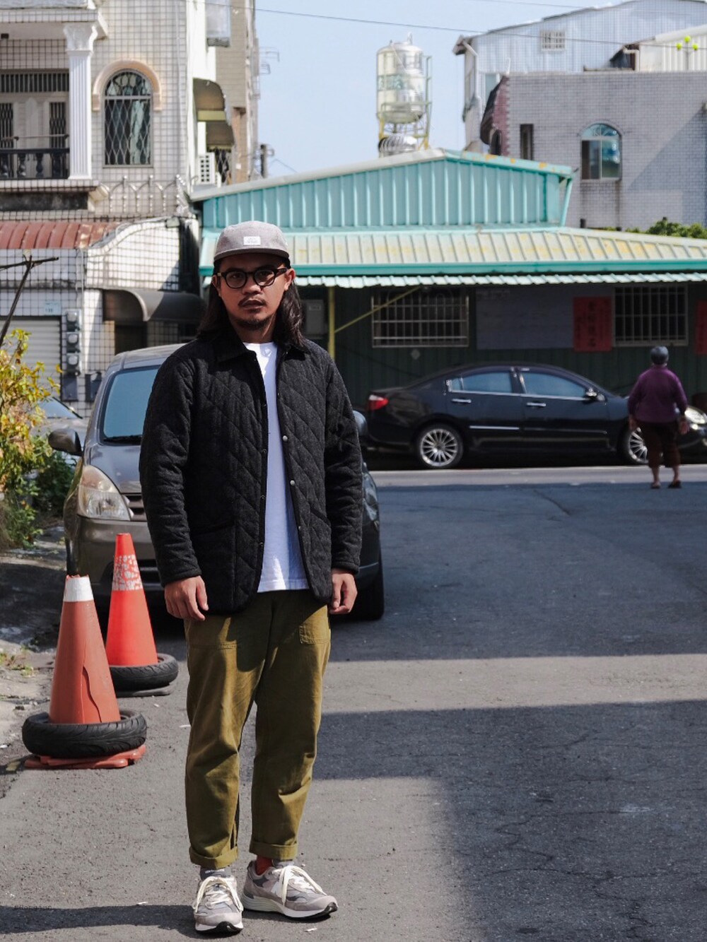 ブラック系のその他アウター、グリーン系のチノパンツ、シルバー系のスニーカーを着用したメンズの冬コーディネートの2枚目の写真