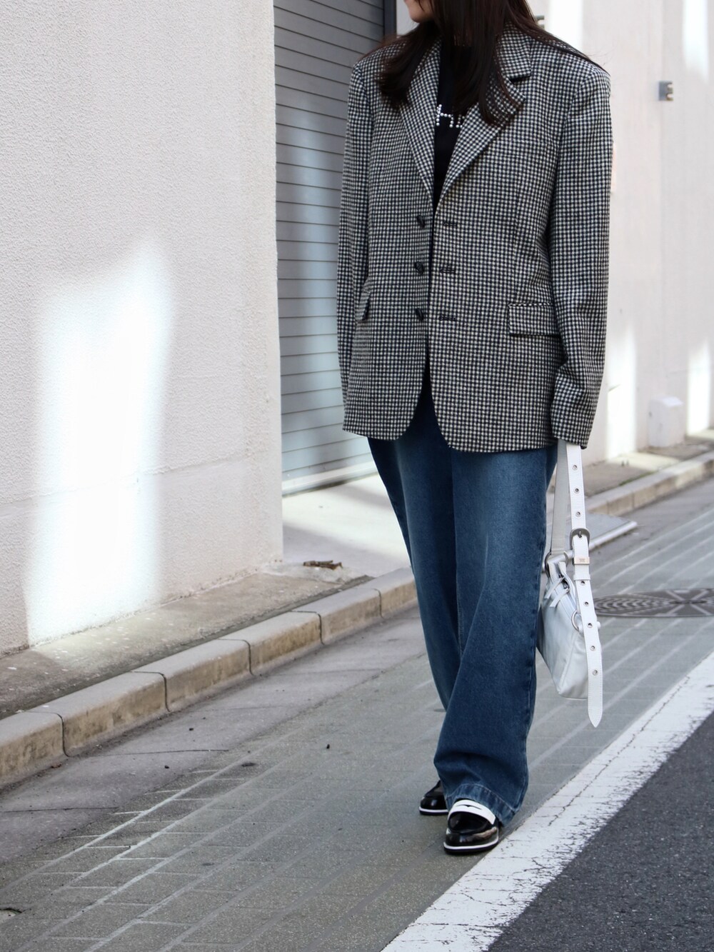 ブルー系のデニムパンツ、ブルー系のデニムパンツ、ホワイト系のショルダーバッグを着用したレディースの春コーディネートの2枚目の写真