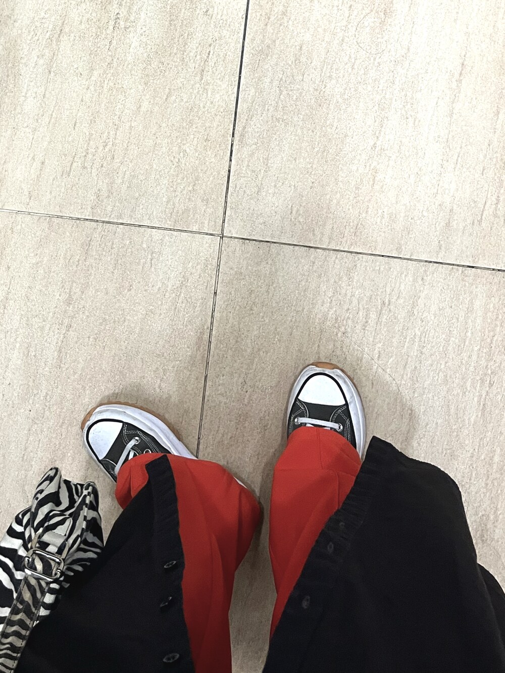 オレンジ系のチノパンツ、ブラック系のショルダーバッグ、ブラック系のシャツワンピースを着用したレディースの春コーディネートの2枚目の写真