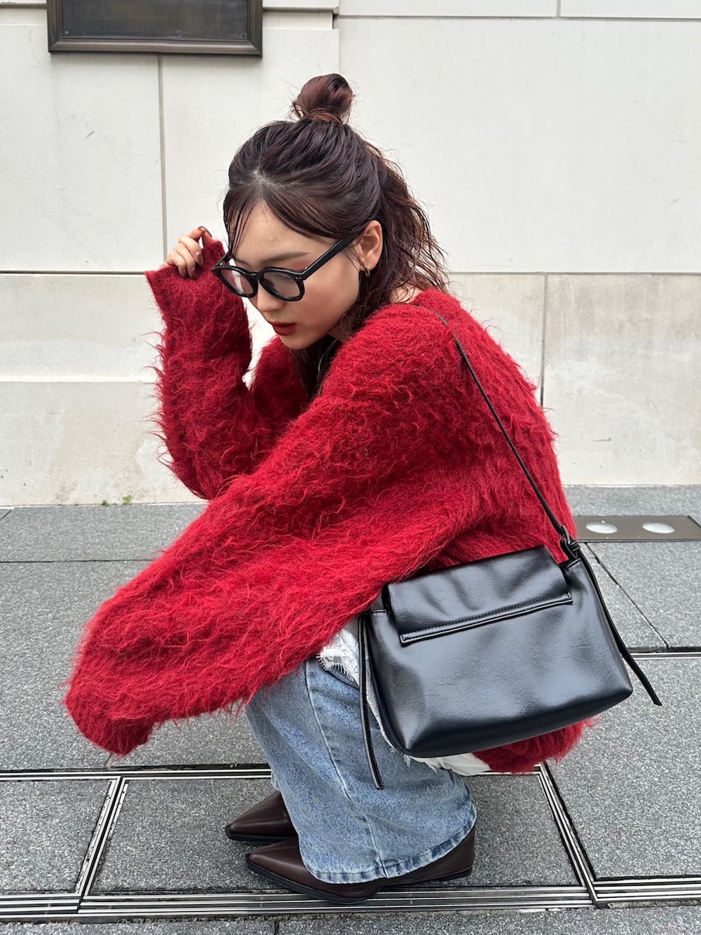 レッド系のニット/セーター、ブルー系のデニムパンツ、ブラック系のショルダーバッグを着用したレディースの秋コーディネートの2枚目の写真
