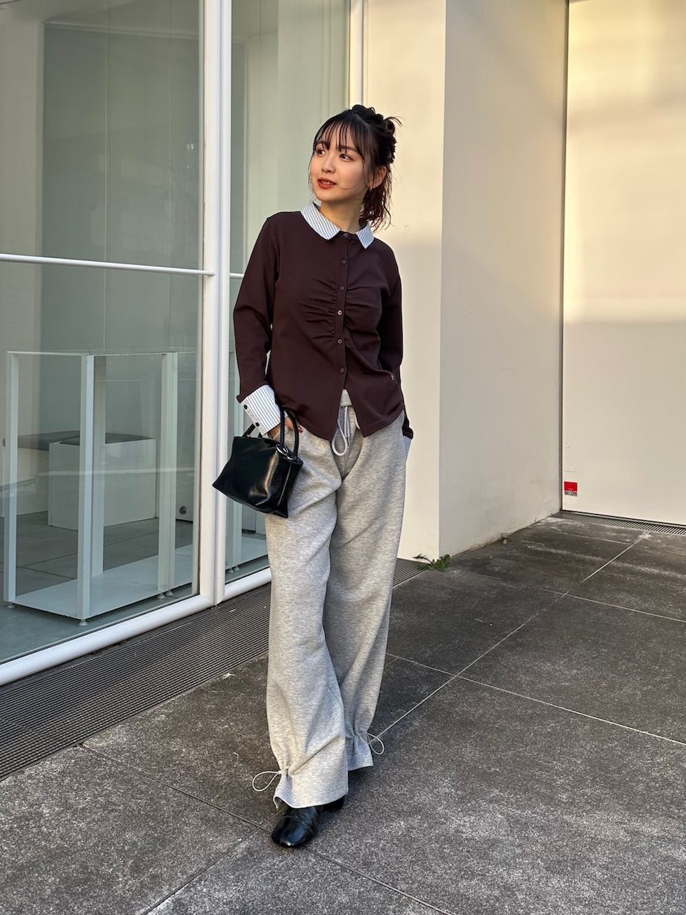 ブラック系のハンドバッグ、グレー系のスウェットパンツ、ブラウン系のTシャツ/カットソーを着用したレディースの冬コーディネートの2枚目の写真