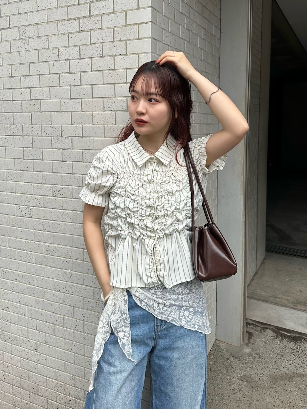 ホワイト系のシャツ/ブラウス、ブルー系のデニムパンツ、ブラウン系のショルダーバッグを着用したレディースの春コーディネートの2枚目の写真
