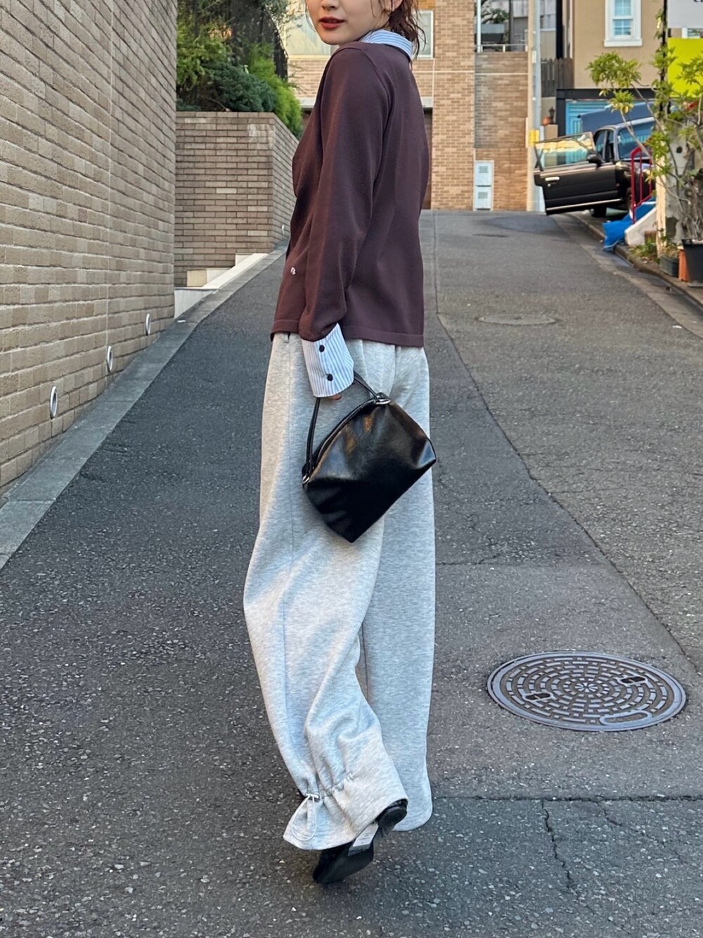 ブラック系のハンドバッグ、グレー系のスウェットパンツ、ブラウン系のTシャツ/カットソーを着用したレディースの冬コーディネートの3枚目の写真