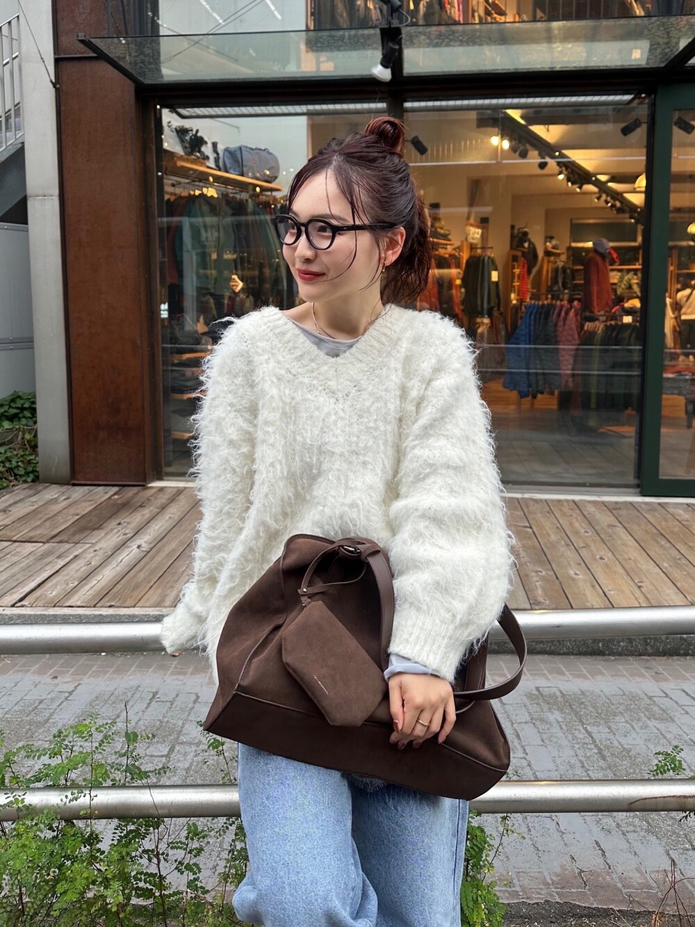 ブルー系のTシャツ/カットソー、ホワイト系のニット/セーター、ブラウン系のボストンバッグを着用したレディースの秋コーディネートの3枚目の写真