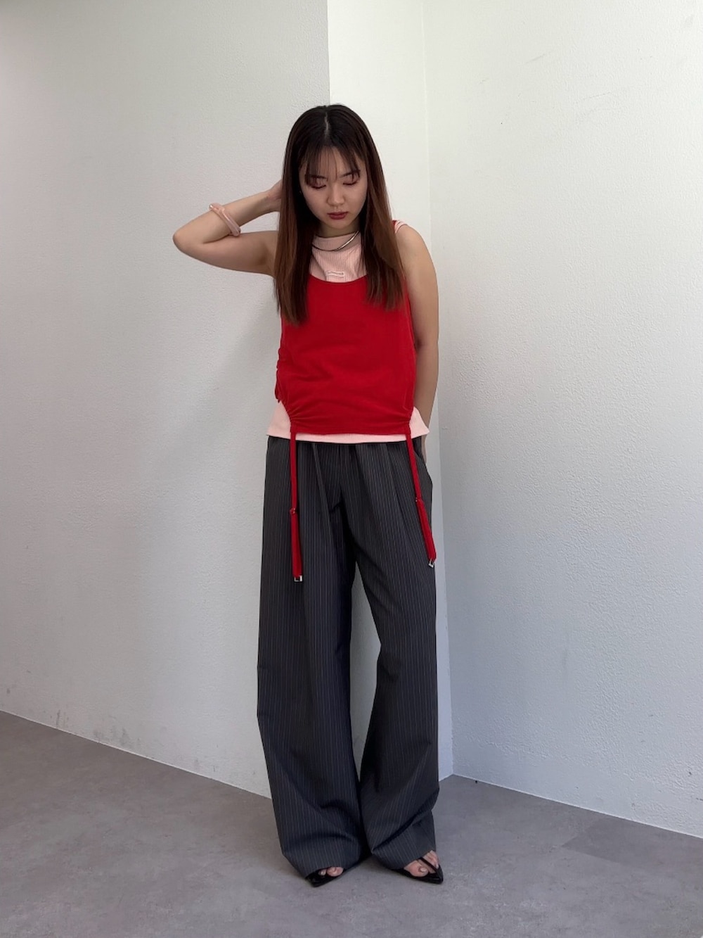 グレー系のスラックス、ピンク系のTシャツ/カットソー、ブラック系のサンダルを着用したレディースの春コーディネートの2枚目の写真